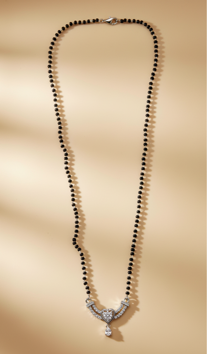 Necklace with black beads and a silver clasp on a beige background