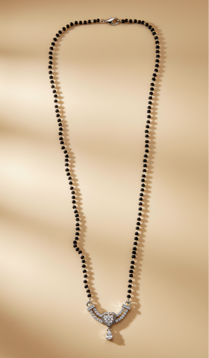 Necklace with black beads and a silver clasp on a beige background